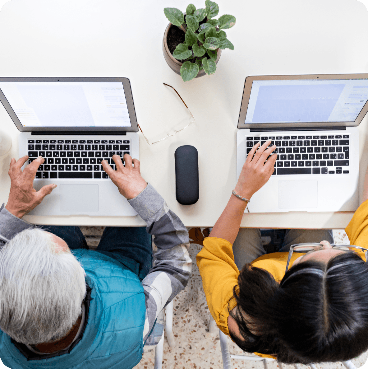 a man and a woman are typing on their laptops
