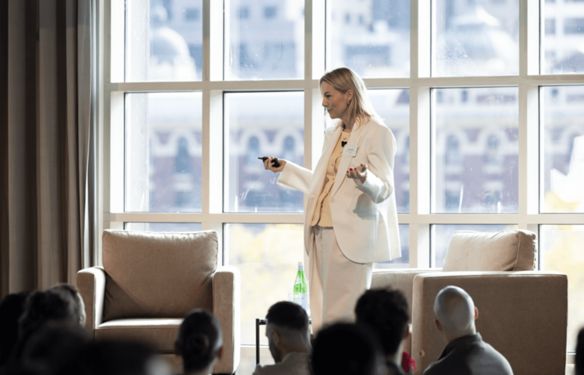 a woman in a white suit is giving a presentation